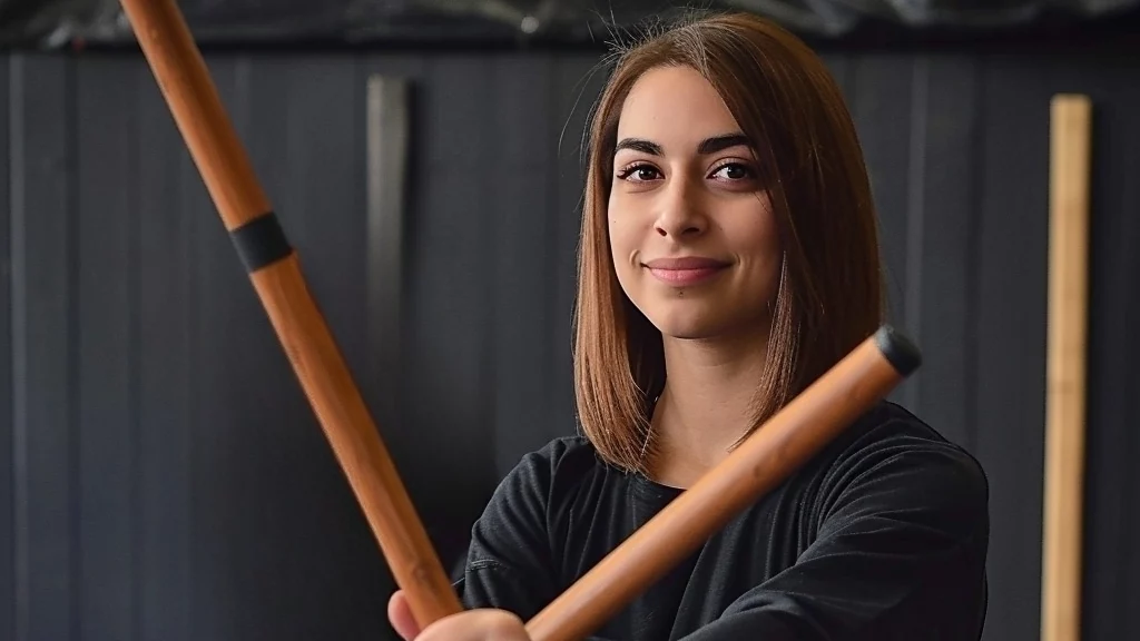 Female Arnis student holding wooden Escrima sticks