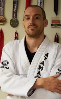 Coach Erik Shiley of River City Warriors standing in front of a wall of medals that he has won in martial arts competitions